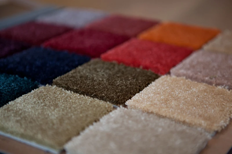 Verschiedene Teppichmuster in mehreren Farben liegen nebeneinander zur Auswahl aus.